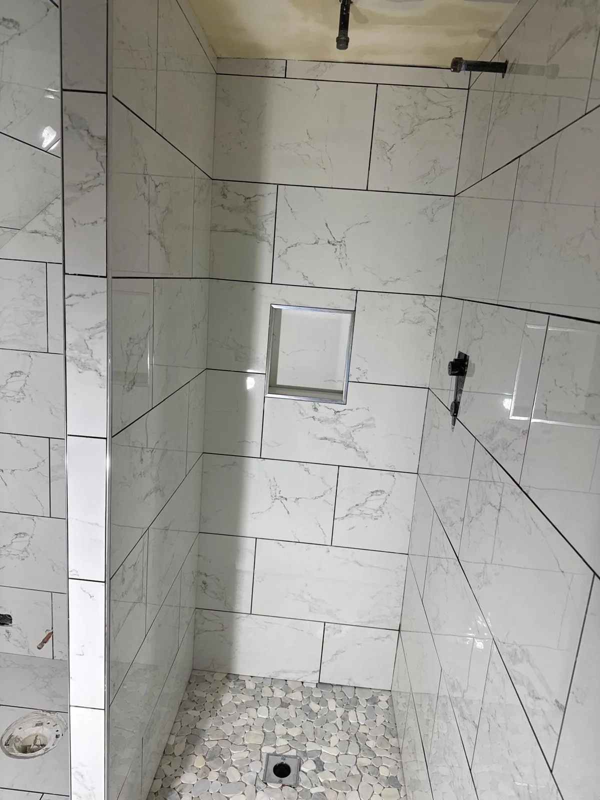 Large marble look shower wall tiles with niche